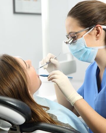 Hygienist checking woman's teeth